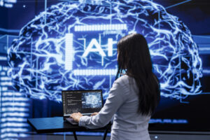 Imagem capa do conteúdo sobre desafios na adoção de ia, onde há uma mulher programadora analisando modelos cerebrais complexos de IA em laptop, executando simulações.