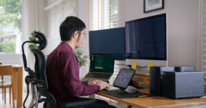Imagem capa do conteúdo sobre teste automatizado em legado .net, onde há um homem asiático de frente para várias telas de computador com códigos.