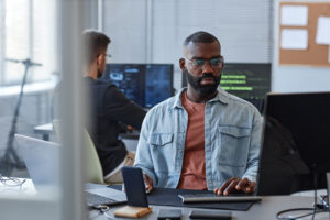 imagem capa do conteúdo sobre IA para líderes, onde há um homem negro de óculos, com barba de frente para o computador.