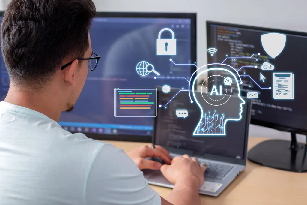 Capa do artigo "IA generativa: o que CIOs e CTOs precisam saber sobre?" com uma foto de um homem branco de costas digitando em seu notebook, na frente dele também estão mais monitores. Na frente do notebook, está uma imagem simbolizando inteligência artificial com uma cabeça humana de perfil e AI no local do cérebro.