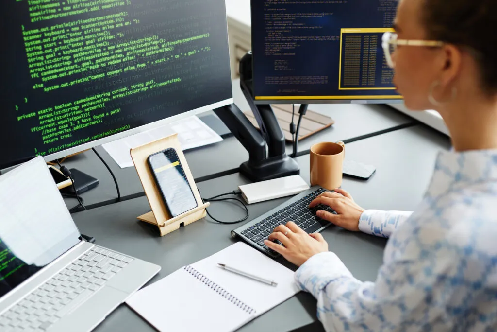 Capa do artigo "Padrões e antipadrões na engenharia de plataforma: dominando e evitando". Imagem com uma Mulher programando em frente ao computador. Na mesa, aparecem duas telas e um celular.