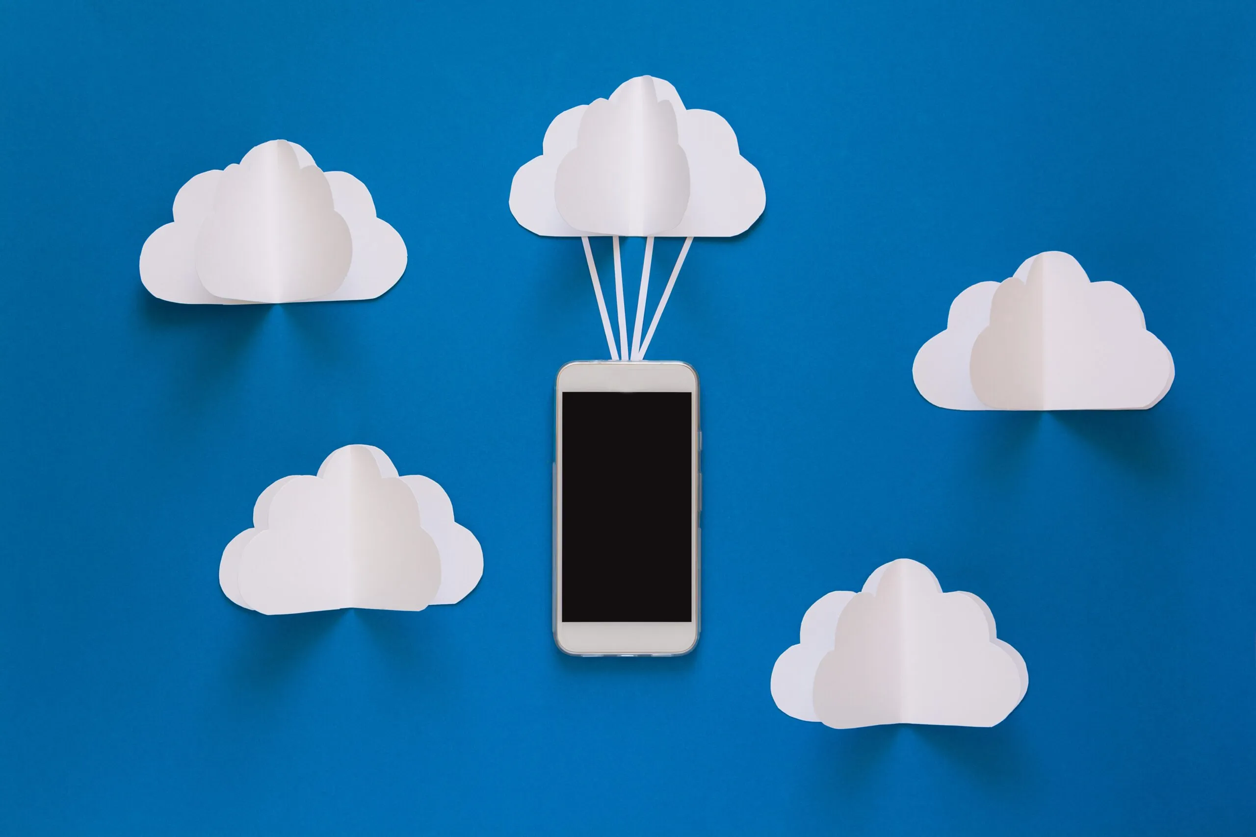 Capa do artigo "O que é cloud storage e erros mais comuns no armazenamento". Imagem com fundo azul como se fosse o céu, com nuvens brancas e ligado a uma delas um celular.