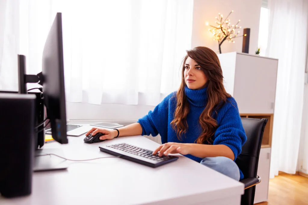 Cover image of the content about Agile Software Delivery, featuring a female web developer facing a computer while working remotely. She is wearing a blue blouse.