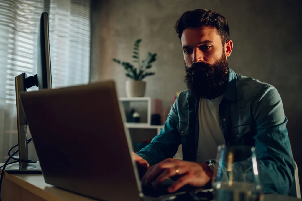 Cover image for the content on continuous reliability, featuring a smart software engineer sitting in his dark home office and coding.