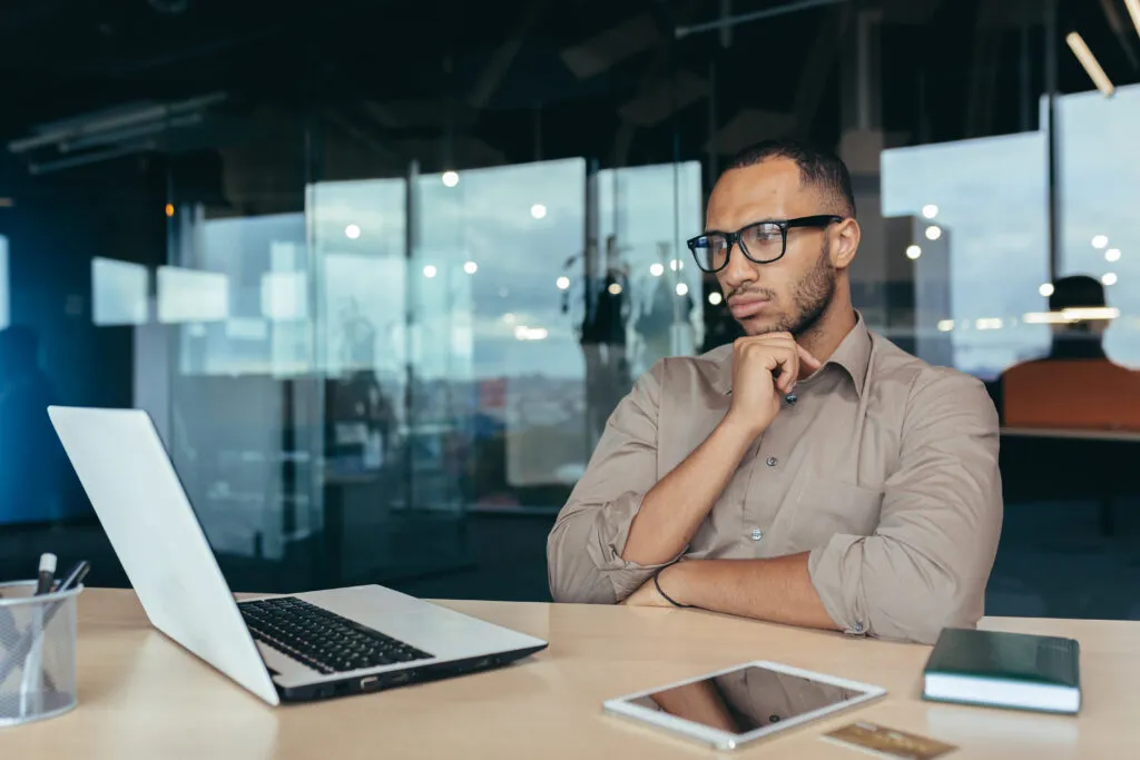 Cover image of the content on Gen AI in legacy modernization, featuring a thoughtful businessman in glasses and a male developer/programmer.