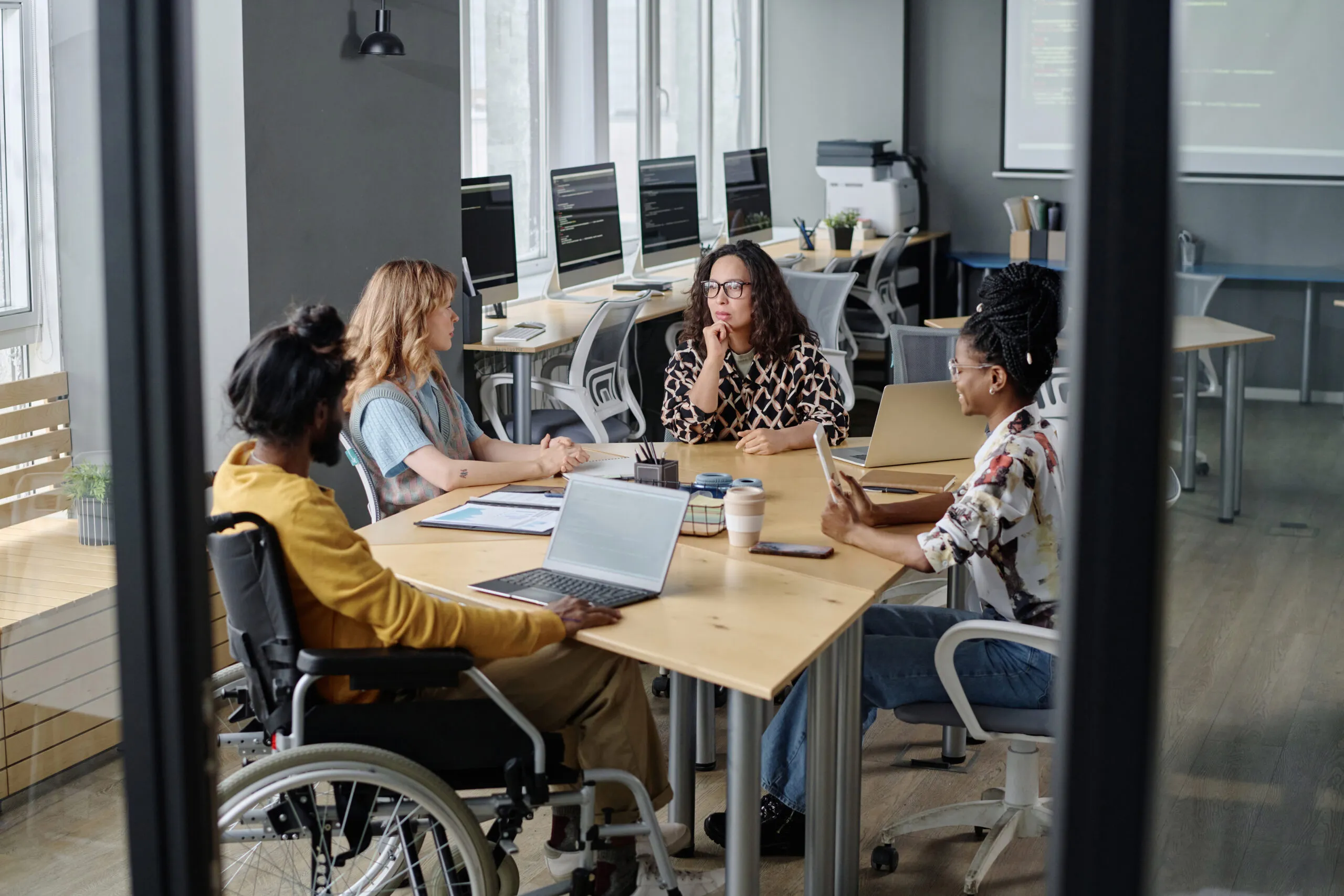 Cover of Gartner's Top Strategic Technology Trends for 2025. Three multi-ethnic women and indian man in wheelchair having business meeting at desk in office.