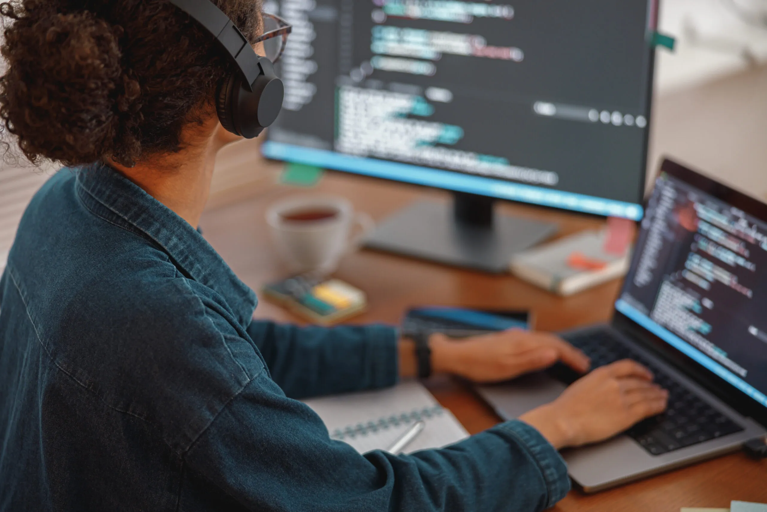 Cover of the article on unit tests for AWS Glue Job. The image shows a white person wearing a headset and a long-sleeved shirt in front of a laptop and monitor in an office environment.