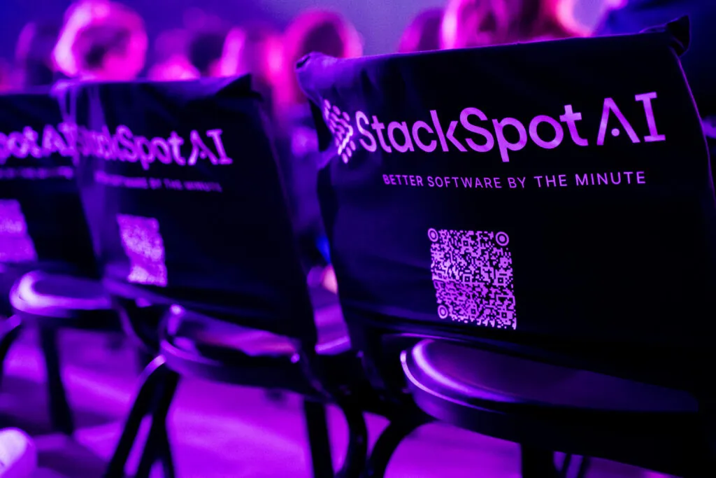Capa do artigo sobre StackSpot AI no Web Summit Rio 2025. Na imagem, temos cadeiras do evento com capas de StackSpot: Better Software by the minute.a